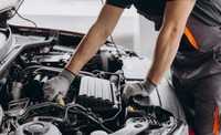 Mechatroniker schraubt am Motor eines Autos herum.