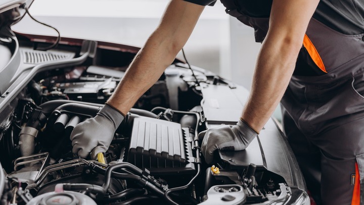 Mechatroniker schraubt am Motor eines Autos herum.