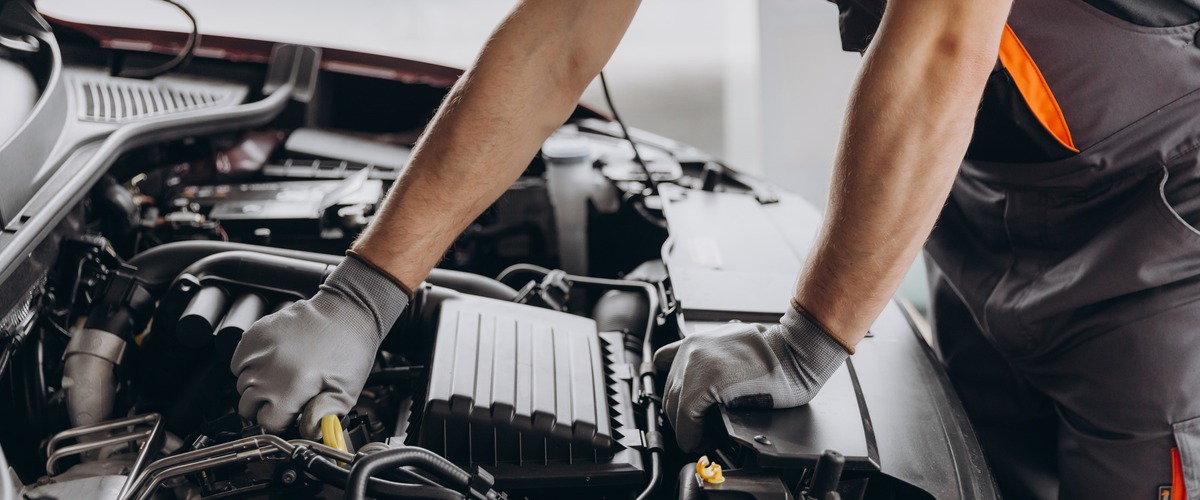 Mechatroniker schraubt am Motor eines Autos herum.