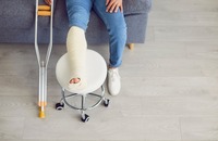 Nahaufnahme eines eingegipsten Beins mit Krücken daneben