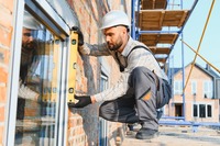 Das Bild zeigt einen Handwerker, der ein Fenster montiert. 