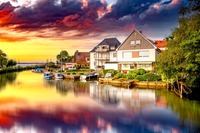 Häuser am Wasser bei einem Sonnenuntergang. Das Bild zeigt Häuser am Wasser beim Sonnenuntergang.