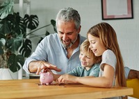 Großvater sitzt mit Enkeln vor einem Sparschwein